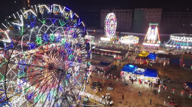 Vibrant Night Carnival Scene Featuring Two Glowing Ferris Wheels and Crowds of People