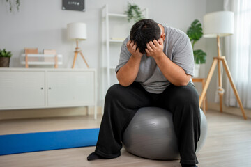 Exhausted Asian plus-size man taking a break while workout in house. 