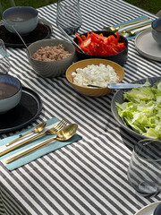 farmhouse dining table with a striped tablecloth topped with freshly baked croissants, quail eggs, avocado, freshly baked bread, and gold cutlery