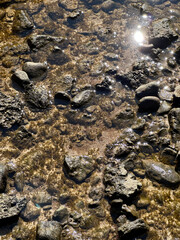 close-up of rocks in a river illuminated by the light of a summer sunset.