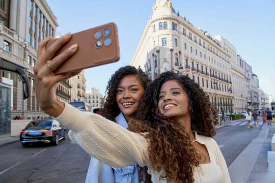 Happy twin sisters taking selfie on city street - Powered by Adobe