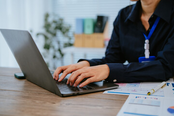 Young Asian businesswoman holding a pen and clipboard, analyzing statistical data on a tablet...