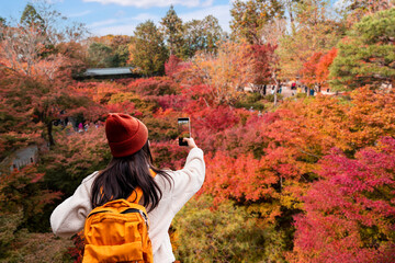 Young woman tourist enjoying autumn leaves at Tofuku-ji Temple in Kyoto, Japan