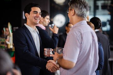 Colleagues in formal and semi-formal attire conversing during a corporate event, checking hand symbolizing leadership, organizational values, and professional growth.