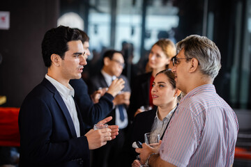 Business team members discussing projects in a networking setting, showcasing collaboration, teamwork, and informal yet professional interaction.