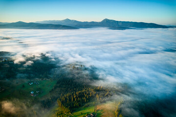 Breathtaking aerial view at dawn, showcasing vast sea of clouds enveloping mountain landscape. Subtle hues of rising sun paint sky in soft pastels, creating tranquil and ethereal scene.