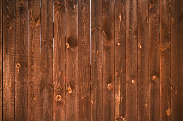 Brown wooden fence with natural grain texture used as background or design element. Wooden planks with knots and lines create rustic pattern for decoration or backdrop