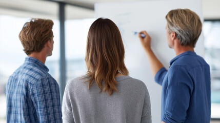 Group of three professionals engaged in a brainstorming session, discussing ideas while standing in front of a whiteboard in a modern office environment, fostering collaboration and creativity