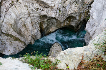 Obraz premium Powerful turquoise river flowing through narrow limestone canyon with white cliffs, dramatic rock formations and foaming water stream in wild untouched natural landscape