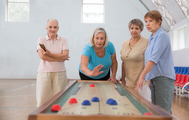 elderly group Playing the board game of shuffleboard.  Kidult gaming in the gym. Active retirement...