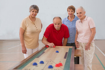 elderly group Playing the board game of shuffleboard.  Kidult gaming in the gym. Active retirement...