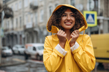 Fototapeta premium Against the building at background. Happy young woman in the city during the rain