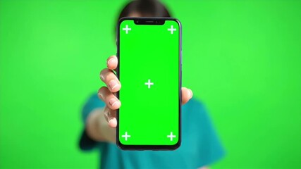 Professional young asian woman in scrubs smiling then presenting smartphone with green screen display motion
