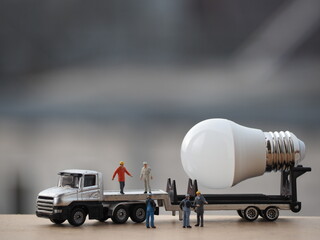 Mini toy of action figure with blurred background. MIniature photography concept design. Minifigure of Worker character with heavy truck and light bulb. Industrial concept.