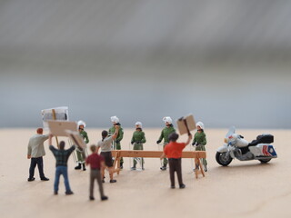 Mini toy of action figure at table with blurred. Toy photography concept. Policeman with demonstration people.