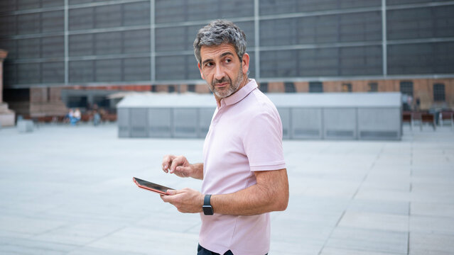 Man looking back using tablet in urban square