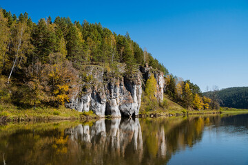 Imagine a picturesque lake that is beautifully surrounded by lush trees and rugged rocks, with a majestic mountain standing tall in the background, creating a stunning natural scene