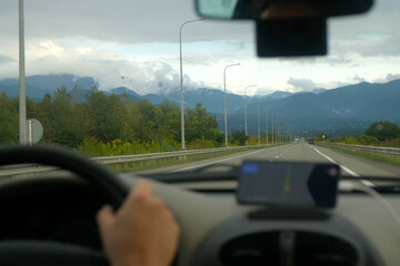Driver driving on highway with scenery mountains view in distance. Navigating mount highway using smartphone gps, following digital route instructions through windshield traveling picturesque roadway.