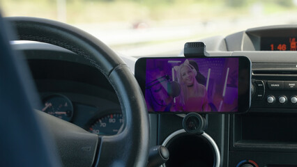 Watching gamer girl livestream on smartphone while driving car on the road