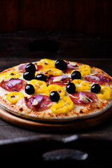 Pizza with chorizo ​​sausage, mozzarella cheese and yellow pepper. Rustic wooden background. Soft focus.	