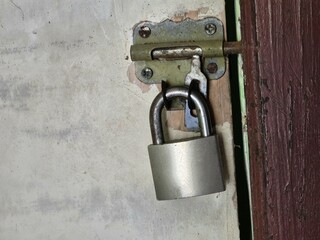 Old wooden door with lock and open padlock showing damaged surface and worn paint