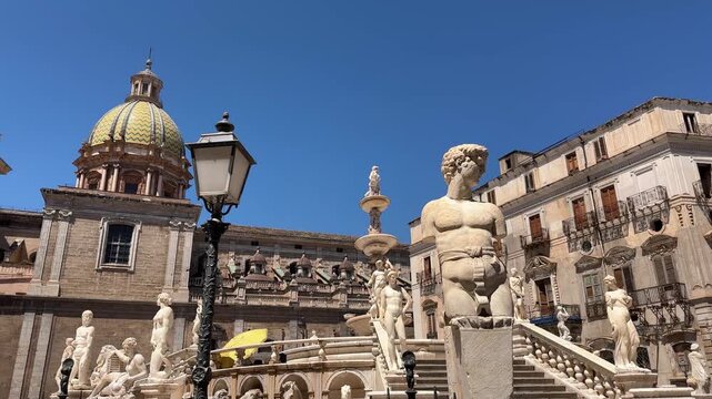 Lateral tracking shot of the marble statues and the monumental Fontana Pretoria in the historic Renaissance square outside Palazzo Pretorio in Palermo, Sicily, Italy.