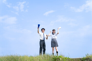 青空をバックに応援する高校生