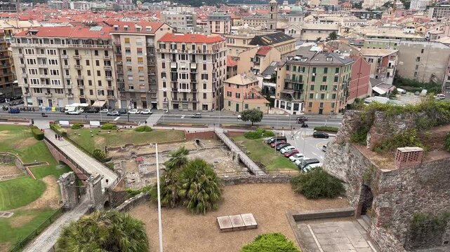 Elevated lateral tracking shot from the Renaissance Priamar Fortress, overlooking the historic cityscape, streets, and architecture of Savona, Italy.