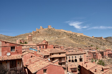 Obraz premium The historic medieval wall of Albarracin, Teruel, protecting the town's reddish houses in the rugged landscape
