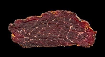 Close-up of a dried beef jerky slice with visible muscle fibers and seasoning against a black background
