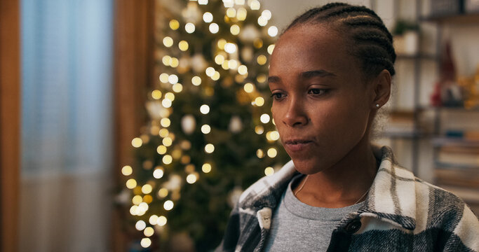 On a winter evening, a young woman of multi-ethnic background sits at a living room table, having a video chat with her boss. Focused, she licks her lips while reporting on the past month's work.