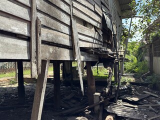 An old wooden house with visible holes and structural damage. The aged timber looks fragile and weathered, showing signs of decay over time.