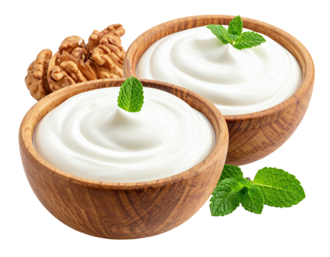 Two wooden bowls of creamy yogurt, topped with fresh mint leaves, and walnuts