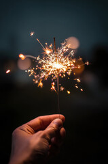 hand of a person holding a sparkler, New Year's Eve celebration concept, blurred background