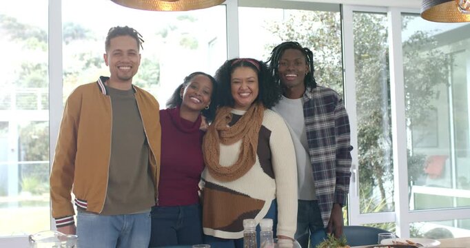 Camera rolling diverse family lining up at dining table with carafe leaning, laughing for portrait