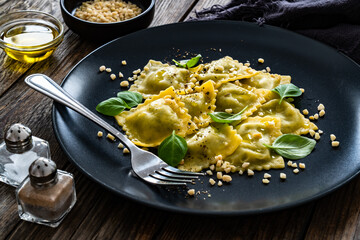Ravioli with basil leaves and pine nuts on wooden table