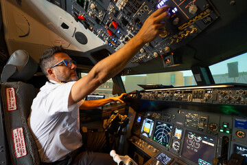 Commercial airline pilot operating controls in cockpit © Martí Rosselló