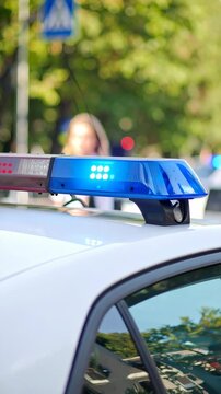 Flashing blue and red lights atop a white patrol vehicle at daytime. Law enforcement and emergency response unit. Vehicle close up.