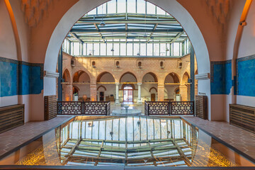 Interior courtyard of Muradiye Madrasa in Bursa with Ottoman arches, columns, fountain and glass roof. 
