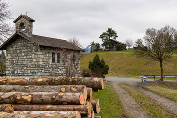 Rustic Stone Chapel and Log Pile in Swiss or Alpine Countryside