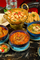 Full Thai Cuisine Feast: Tom Yum Goong, Green Curry, Red Curry, and Massaman Served on a Dark Table