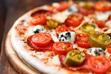 Pizza with salami, jalapeno pepper, cherry tomatoes and mozzarella cheese. Soft focus.	