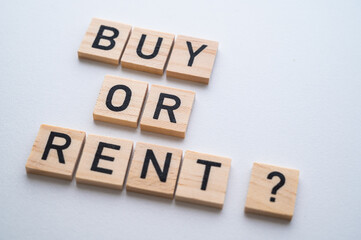 Buy or rent text composed with wooden alphabet, and coins next to it, on a white background. Option between renting and buying.