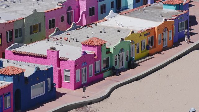 A row of vibrant Spanish style cottages in Capitola, California, with bright colors and tiled roofs, captured with slight camera motion on a sunny day.