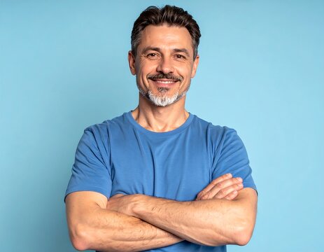 Smiling middle-aged man, arms crossed, against a light blue background.  Friendly, confident expression