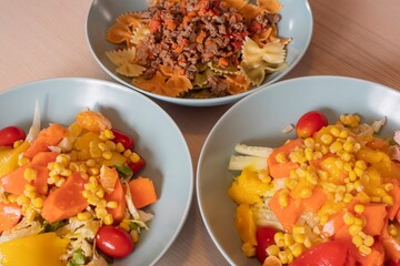 Fitness nutrition bowls with pasta, lean meat and fresh vegetable salad. Balanced diet with corn, peppers, lettuce and tomatoes. Healthy lifestyle and clean eating background for diet concept.