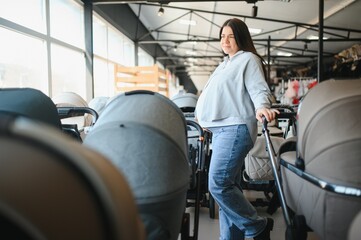 Young pregnant woman in shop of children goods. The choice for a baby stroller