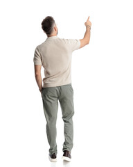 back view of casual young man pointing finger far away while walking