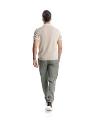 back view of casual young man stepping forward with hand in pocket