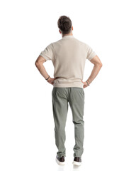 casual young man with polo shirt holding hands on hips and walking